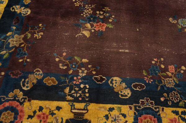 Maroon, blue, and gold rug detail showing complex floral sprays, cloud shapes, and border patterns.