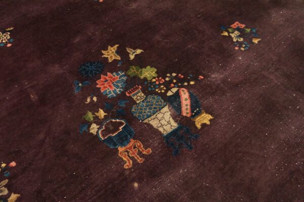 A low-pile rug with a dark purple field and colorful stylized floral vase patterns.