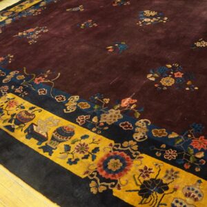 Aubergine rug with scattered floral bouquets, featuring wide gold and navy borders on light wood flooring.