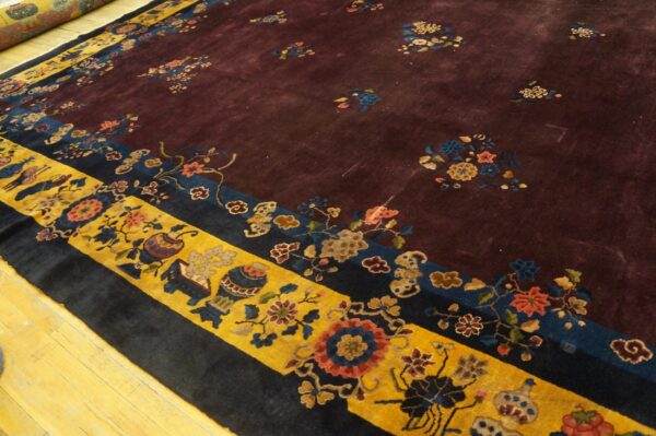 Aubergine rug with scattered floral bouquets, featuring wide gold and navy borders on light wood flooring.
