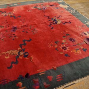 Vivid red plush rug with scattered floral and ribbon motifs, framed by a dark blue-green patterned border on wood floors.