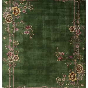 A deep green rug with an ornamental mauve border depicting bamboo and multi-colored floral sprays.