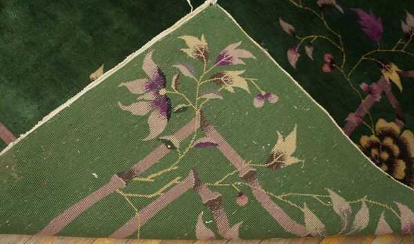 A dark green floral rug is folded back, revealing the reverse side with woven tan and purple patterns.