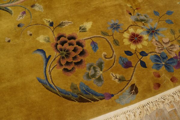 A golden yellow rug featuring detailed florals in blue, red, and rust colors with cream fringe.