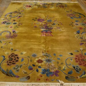 Golden yellow high-pile rug featuring a traditional floral vase centerpiece and scrolling borders on wood flooring.