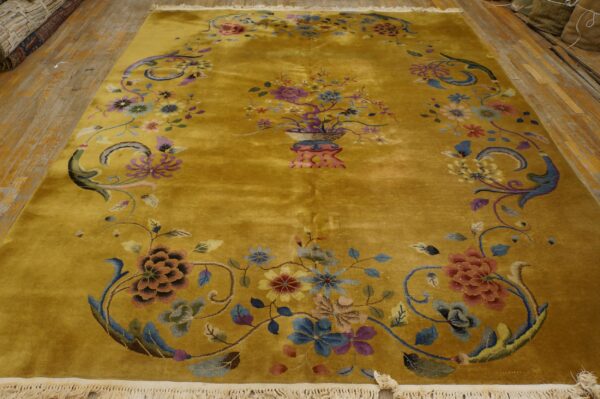 Golden yellow high-pile rug featuring a traditional floral vase centerpiece and scrolling borders on wood flooring.