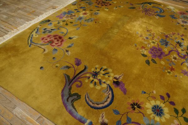 Mustard yellow rug with a sheen and intricate multicolored floral pattern sits on distressed wood flooring.