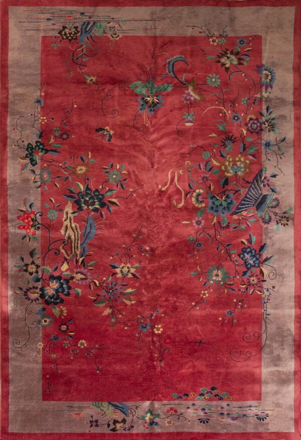 A high-pile red rug displays elaborate multicolored floral vines and birds within a wide taupe border.
