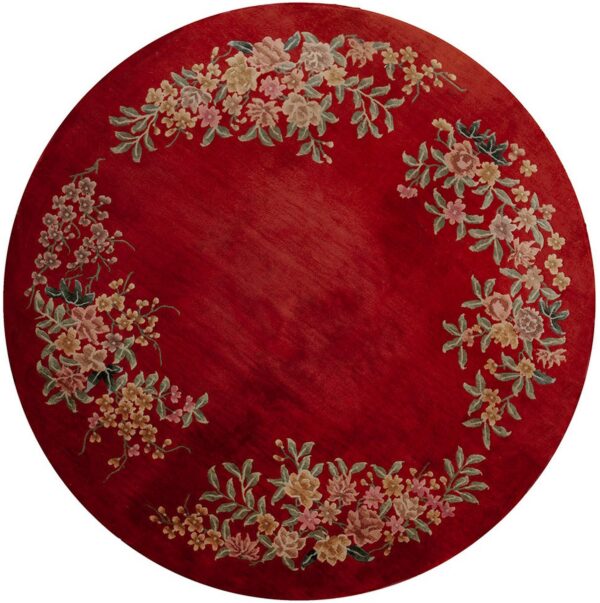 Round red rug featuring a plush pile texture and a multicolored floral wreath around the center field.