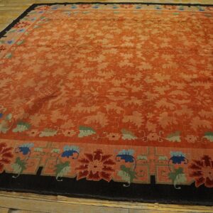 Large rust-colored rug with tone-on-tone vines and borders featuring stylized blue, red, and green flowers on wood floors.