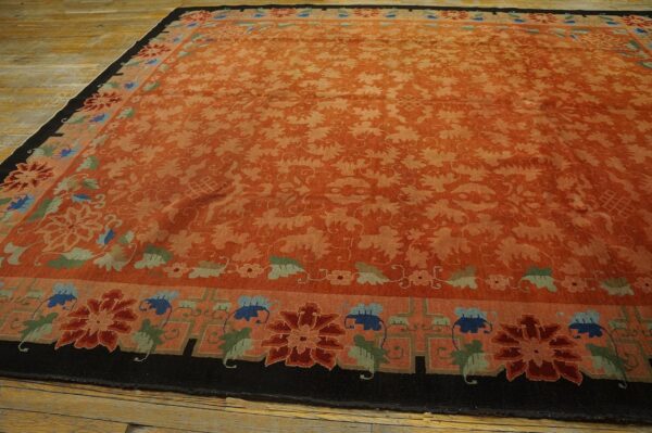 Large rust-colored rug with tone-on-tone vines and borders featuring stylized blue, red, and green flowers on wood floors.