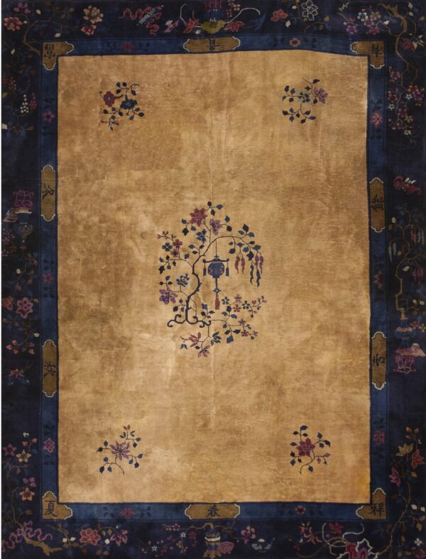 Tan rug with a high sheen, contrasted by a dark blue border filled with detailed multicolored florals.