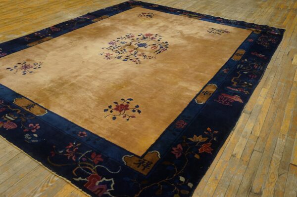Gold and navy rug with floral patterns centered on distressed light wooden plank flooring.