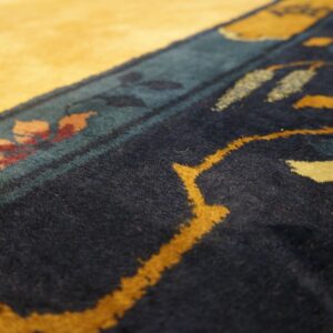 A plush rug border features golden yellow, dark navy, teal, and burgundy floral patterns.