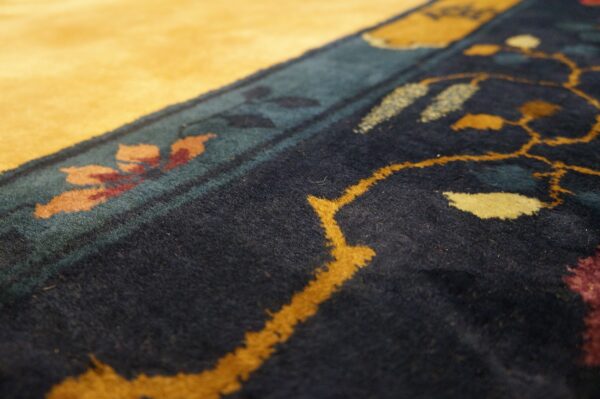 A plush rug border features golden yellow, dark navy, teal, and burgundy floral patterns.