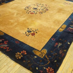 Gold field rug with blue and red floral patterns, surrounded by a detailed navy blue border on wood floors.