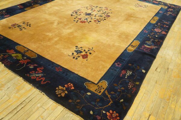 Gold field rug with blue and red floral patterns, surrounded by a detailed navy blue border on wood floors.