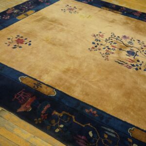 Gold high-pile rug with a wide navy border and stylized red and blue florals on distressed wood flooring.