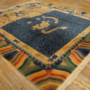 Blue and tan dragon rug featuring a rainbow wave border sits on distressed yellow wood floors.
