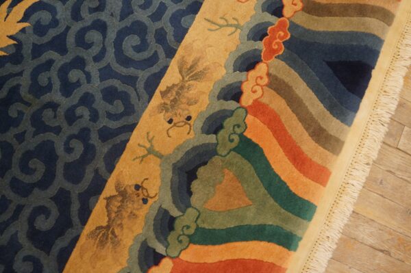 Colorful rug detail featuring dark blue scrolls, stylized gold figures, and thick stripes on wood flooring.