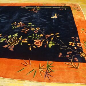 Navy blue rug with multicolored floral vines and a butterfly motif inside a wide orange border.