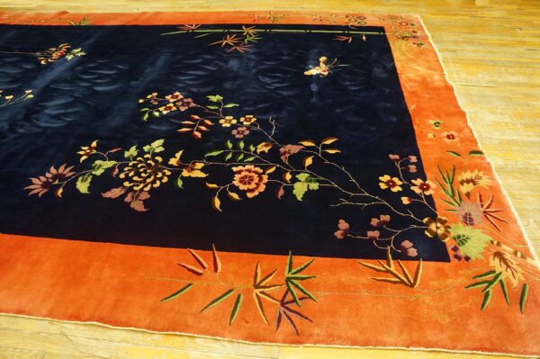 Navy blue rug with multicolored floral vines and a butterfly motif inside a wide orange border.