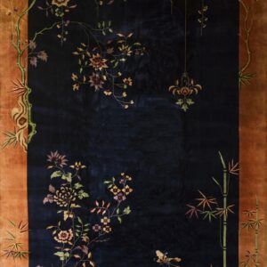 Deep navy rug with elaborate multicolored floral and bamboo patterns set within a rustic orange border.