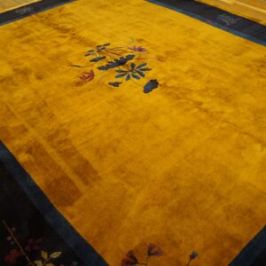 Large golden yellow rug with a navy border and blue floral pattern rests on hardwood floors.