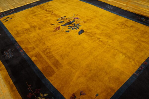 Large golden yellow rug with a navy border and blue floral pattern rests on hardwood floors.