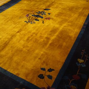 Gold rug with high pile texture and a wide navy border featuring detailed floral and character motifs.