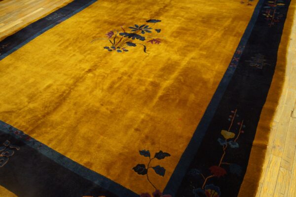 Gold rug with high pile texture and a wide navy border featuring detailed floral and character motifs.