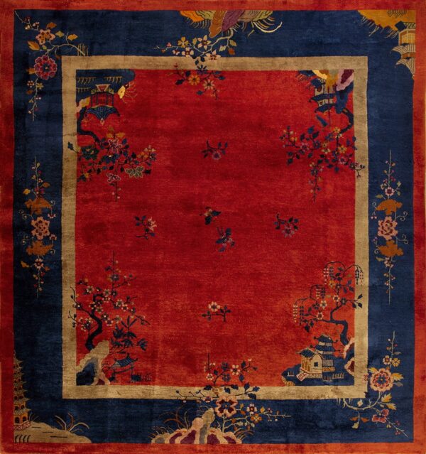 Red square rug with a navy blue border and elaborate multicolor flowering tree and pagoda designs.