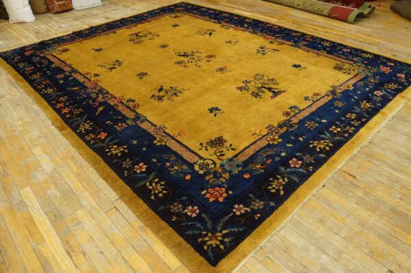 Mustard yellow rug with navy floral borders and scattered motifs, displayed on light wood floors.