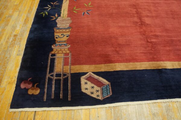 Rust field and navy border rug featuring a potted plant pattern resting on yellow hardwood planks.