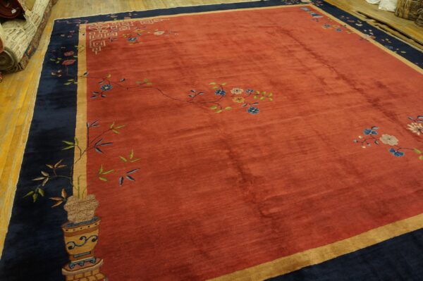Red field rug with navy border and gold guard stripe featuring colorful vines and stylized blossoms.