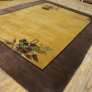Golden-yellow rug with a dark brown border and colorful corner floral designs on plank wood floor.