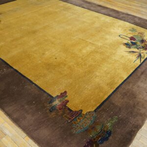 Golden yellow rug with a wide brown border and colorful floral corner motifs on light wood floors.