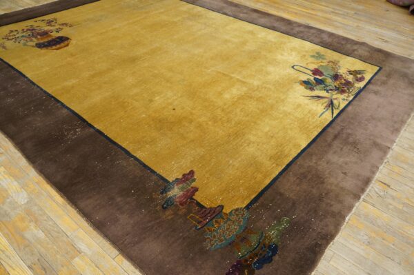 Golden yellow rug with a wide brown border and colorful floral corner motifs on light wood floors.