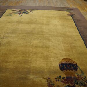Yellow gold rug featuring stylized vase motifs and a broad brown border on rustic wood flooring.