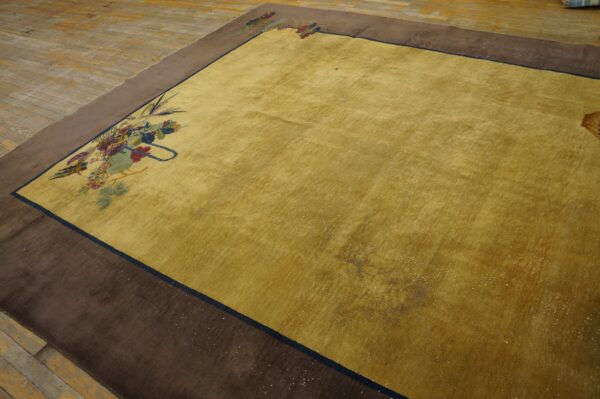 Low-pile golden yellow rug featuring corner floral details and a broad solid brown outer border on wood flooring.