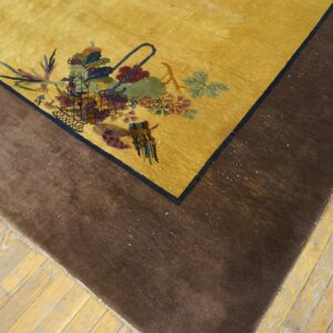 Yellow rug with a multicolored floral basket motif and wide dark brown border on light wood floors.
