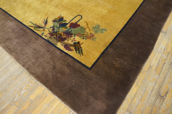Yellow rug with a multicolored floral basket motif and wide dark brown border on light wood floors.