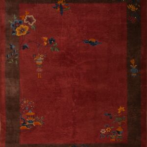 Red field rug with deep brown border features sparse multicolored floral and architectural motifs.