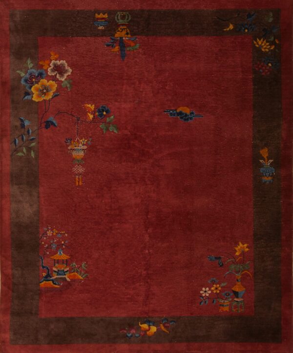 Red field rug with deep brown border features sparse multicolored floral and architectural motifs.