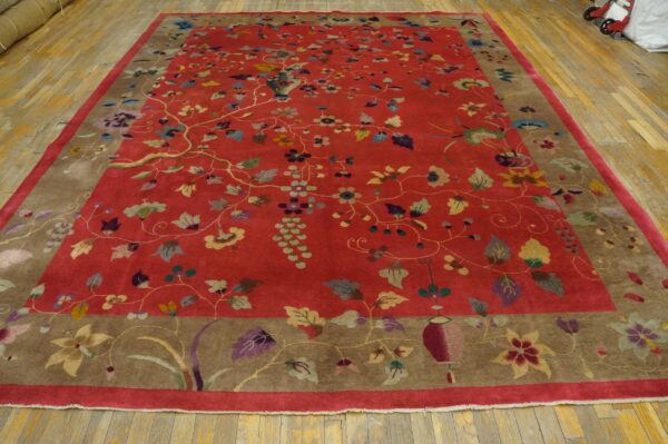 High-pile red rug features an elaborate multi-colored floral pattern with a wide brown border on wood planks.