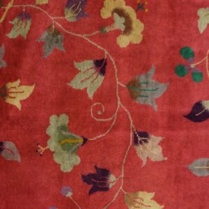 High-pile red rug detail featuring a flowing floral pattern in muted sage, gold, and deep purple.