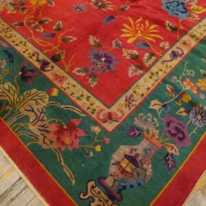 Close-up of a high-pile rug featuring a coral field, teal border, and multicolor floral motifs on wood flooring.