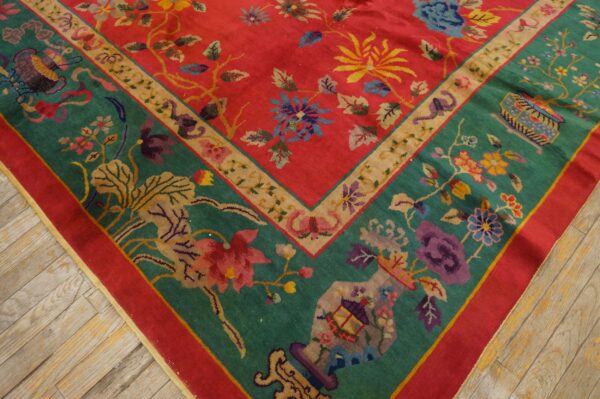 Close-up of a high-pile rug featuring a coral field, teal border, and multicolor floral motifs on wood flooring.