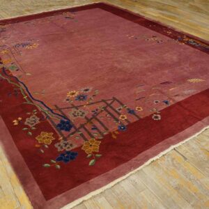 Plush mauve rug with a maroon border and scattered multicolored flowers on worn wooden floorboards.