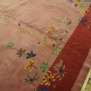 High pile blush rug featuring scattered stylized flowers and a prominent, solid red vertical border.